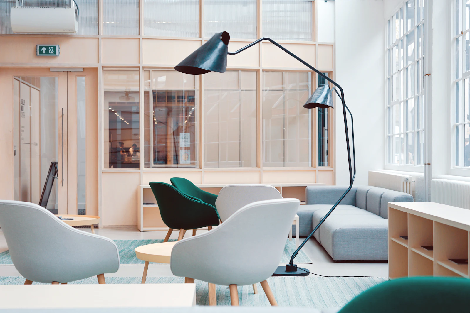Ljus lounge med gröna fåtöljer och stora fönster